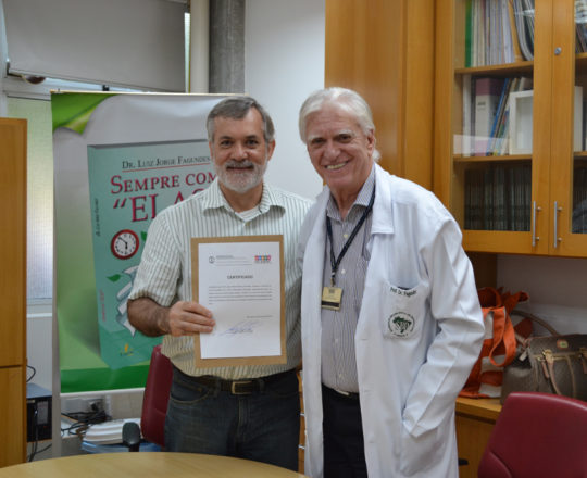 O Prof. Dr. Luiz Jorge Fagundes, no momento da entrega do Certificado de Palestrante ao Prof. Lucas Blanco.
